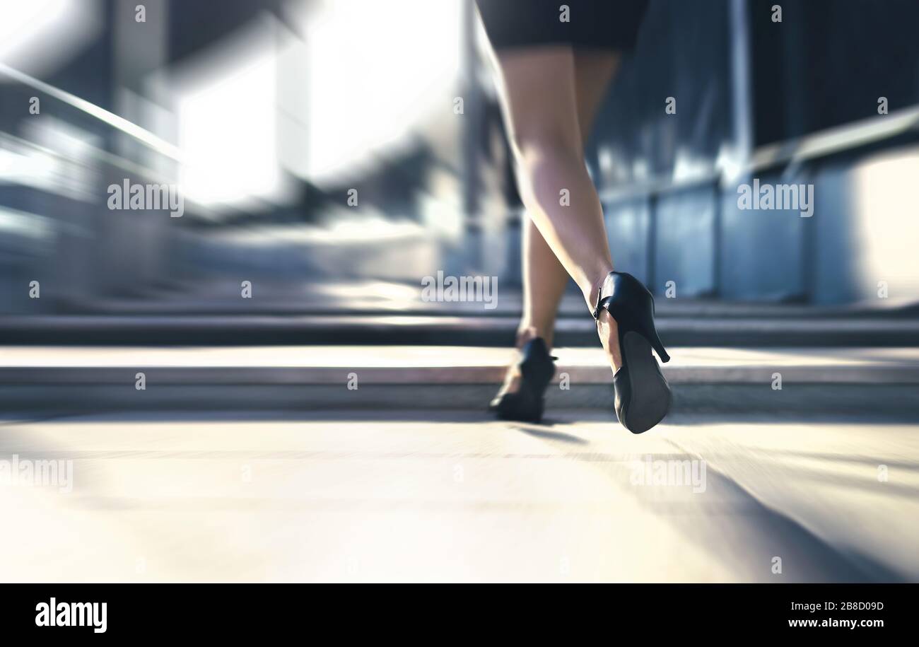 Mujer corriendo o caminando rápido con tacones altos en la calle de la ciudad. Ocupado persona de negocios en prisa. Tarde del trabajo o el estrés rápido. Escaleras Sprint. Foto de stock