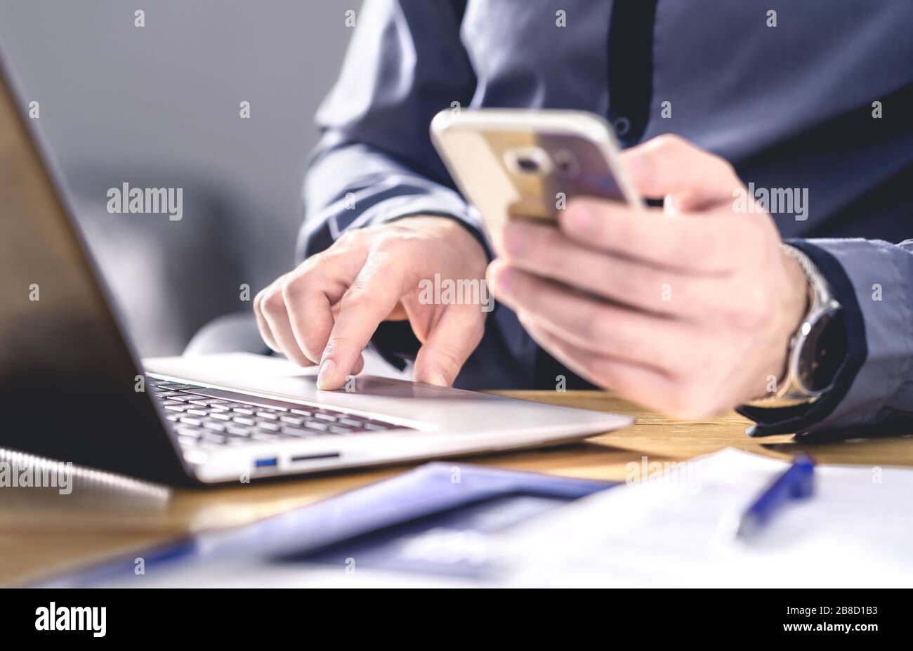 Multitarea y tecnología móvil. Hombre de negocios ocupado con el teléfono y el portátil. Empresario trabajando duro con el smartphone y la computadora. Foto de stock