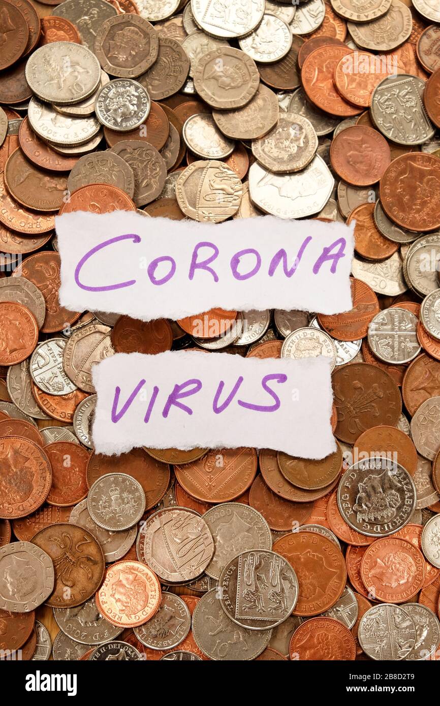 Las palabras corona virus escrito en tinta púrpura en dos pedazos de papel blanco rasgado encima de cientos de monedas de color plata y cobre, libra Foto de stock