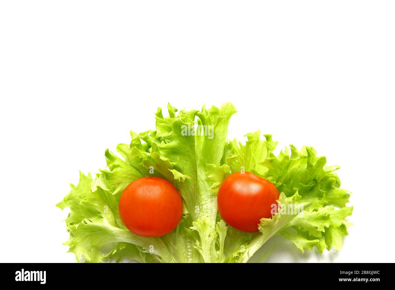 Tomates cherry rojos y hojas de lechuga sobre fondo blanco Foto de stock