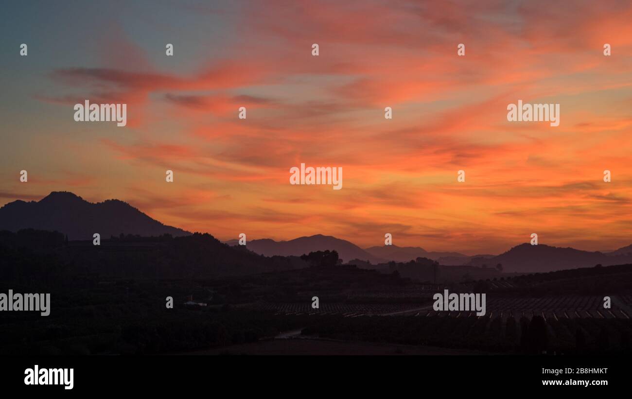 Hermosos colores en el cielo durante una puesta de sol sobre las colinas españolas en la región Valenciana Foto de stock