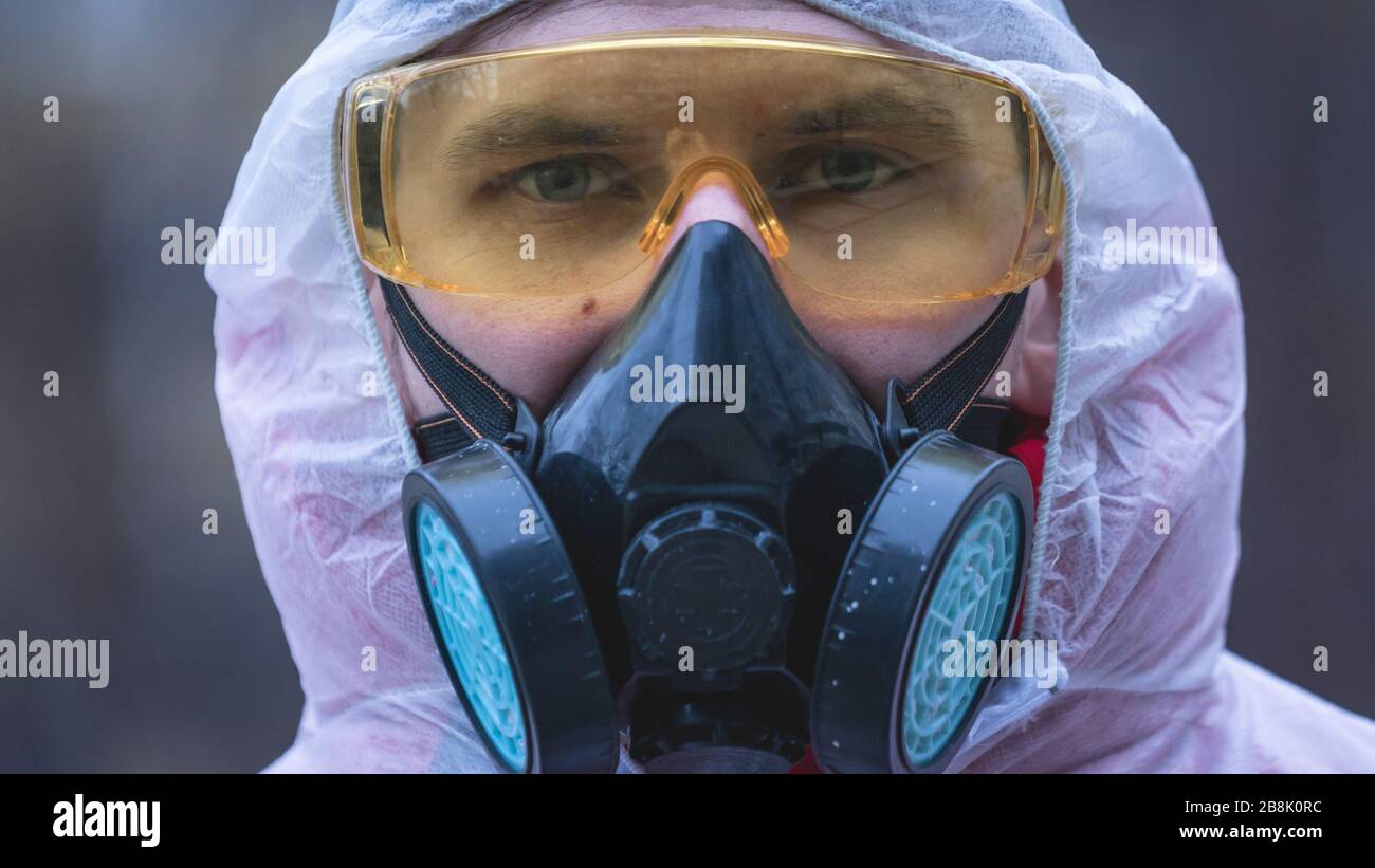 El joven europeo hombre en traje químico protector y respirador, al aire libre. Nuevo coronavirus (COVID-19). Concepto de atención de salud durante una epidemia o. Foto de stock