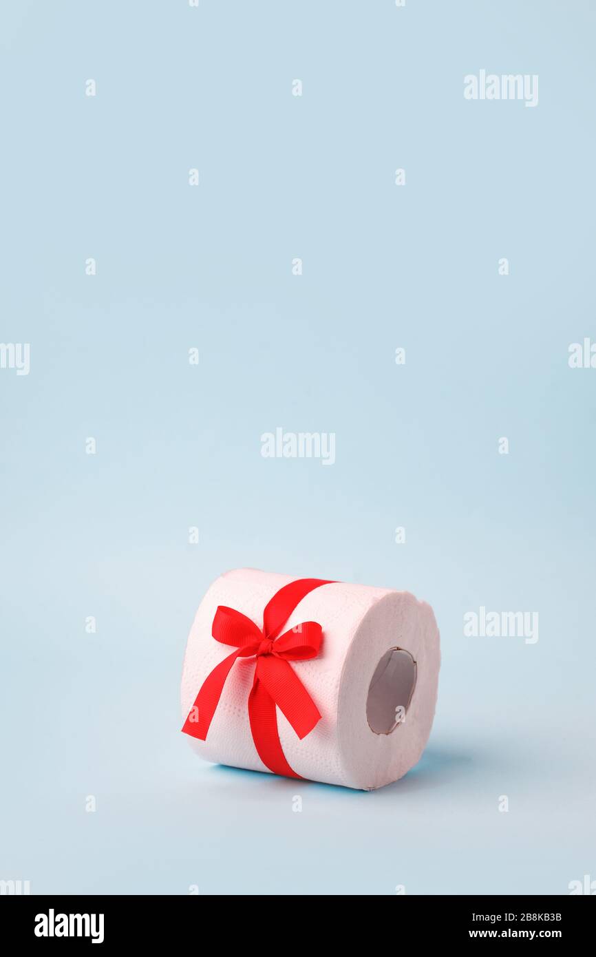 Un rollo de papel higiénico envuelto en un arco de regalo. El concepto de  un valioso regalo real, un meme sobre el déficit en los supermercados,  coronavirus covid-19, pani Fotografía de stock -