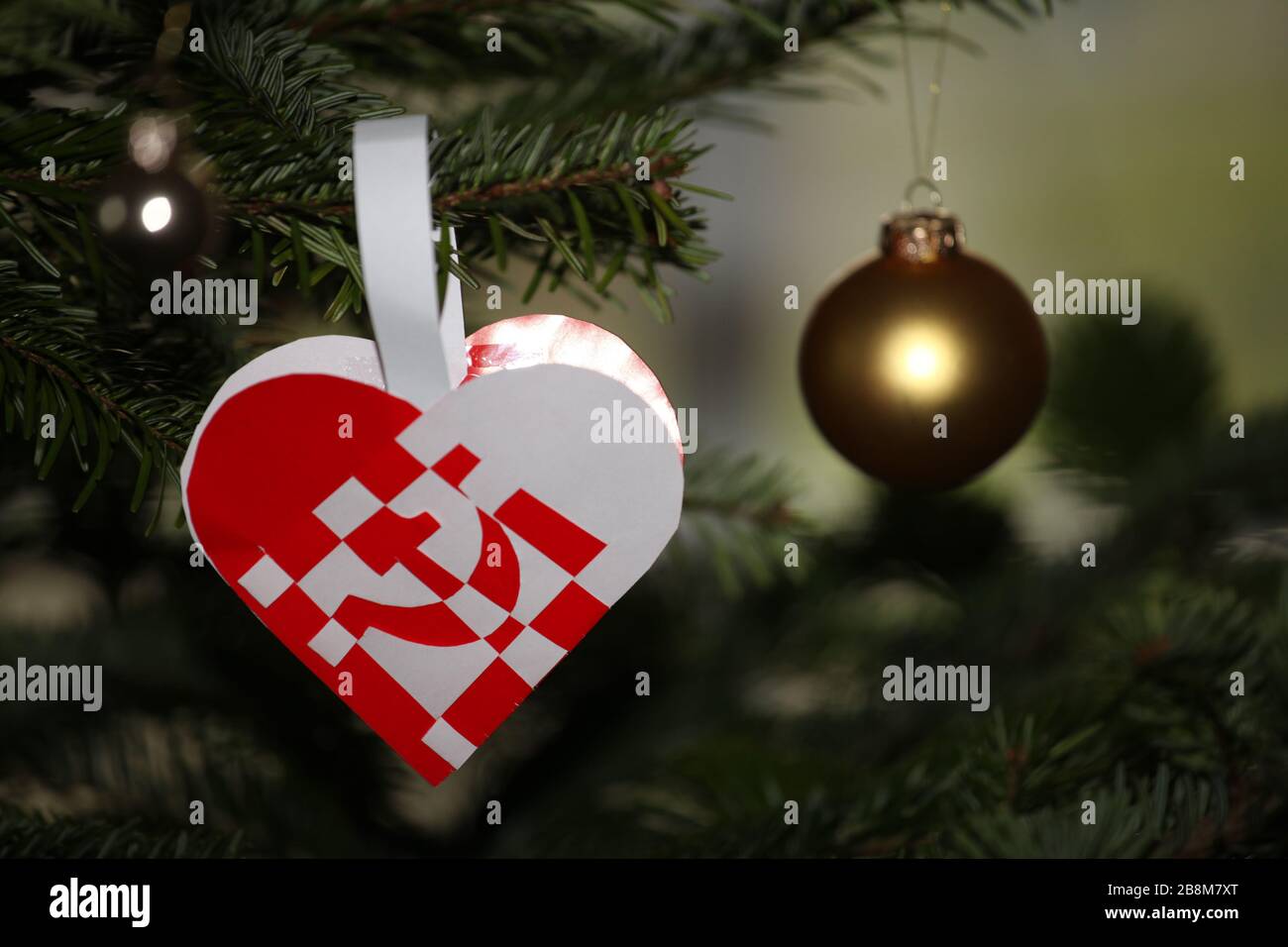 Corazón de Navidad con protesta contra el capitalismo. Martillo y hoz. Foto de stock