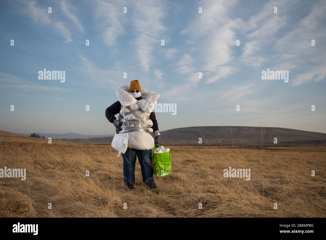 Perthshire Hills, Reino Unido. 22 de marzo de 2020. En la imagen: Imagen conceptual de una persona que va a longitudes extremas para auto aislar en el medio de la nada llevar el artículo más buscado en el mundo del papel higiénico, mientras que envuelto en el hogar hizo equipo de protección personal. Crédito: Colin Fisher/Alamy Live News Foto de stock