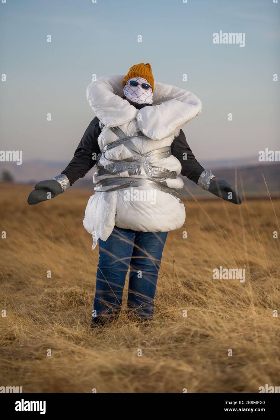 Perthshire Hills, Reino Unido. 22 de marzo de 2020. En la imagen: Imagen conceptual de una persona que va a longitudes extremas para auto aislar en el medio de la nada llevar el artículo más buscado en el mundo del papel higiénico, mientras que envuelto en el hogar hizo equipo de protección personal. Crédito: Colin Fisher/Alamy Live News Foto de stock