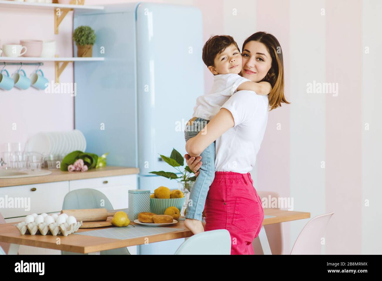 Hermosa madre y pequeño hijo se están amotando en la cocina, tiempo feliz y la unión Foto de stock