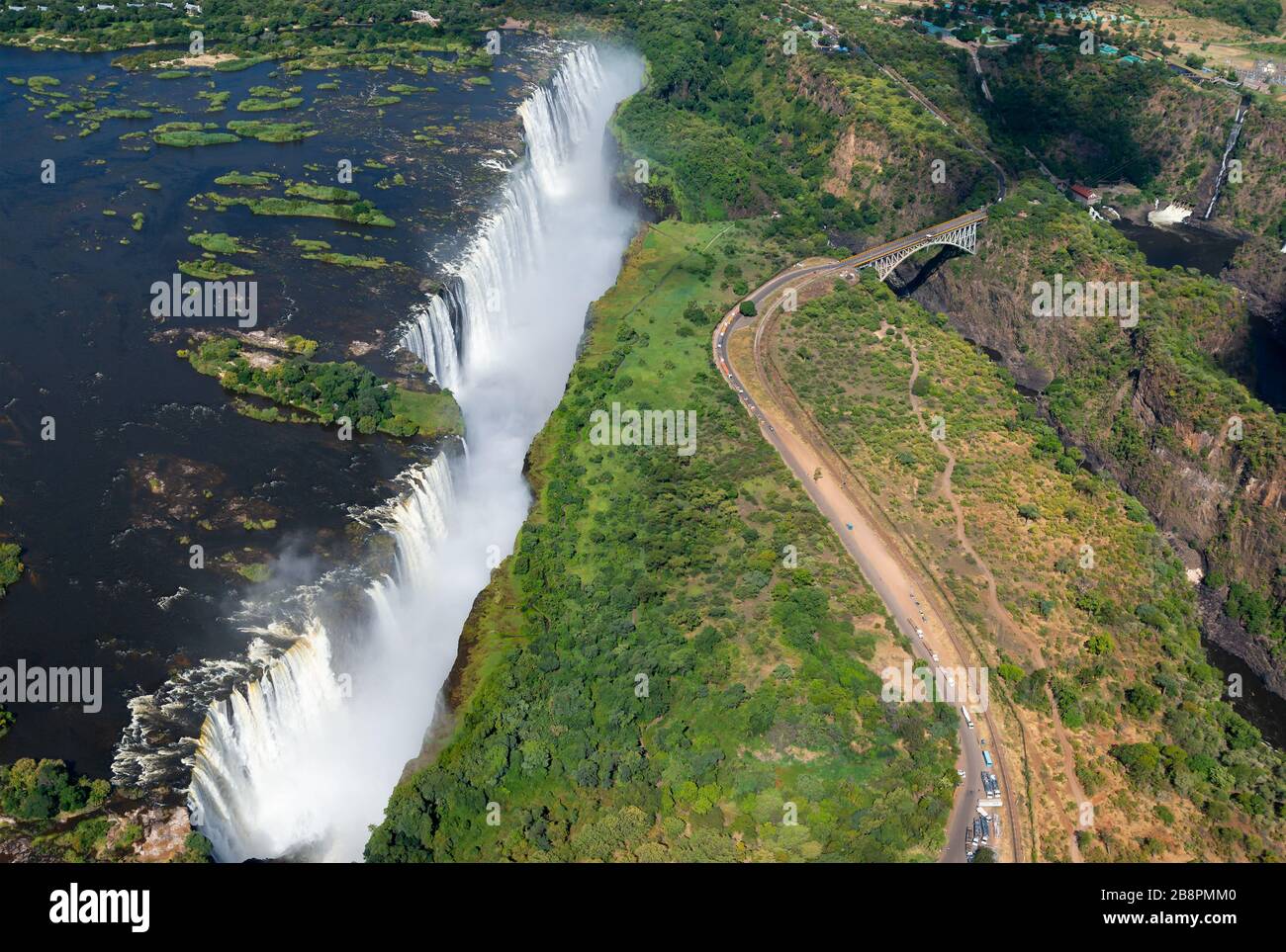 Vista aérea de las Cataratas Victoria situadas entre Zimbabwe y Zambia en un día soleado. Agua que fluye desde el río Zambezi. Catalogado por la UNESCO como Patrimonio de la Humanidad Foto de stock