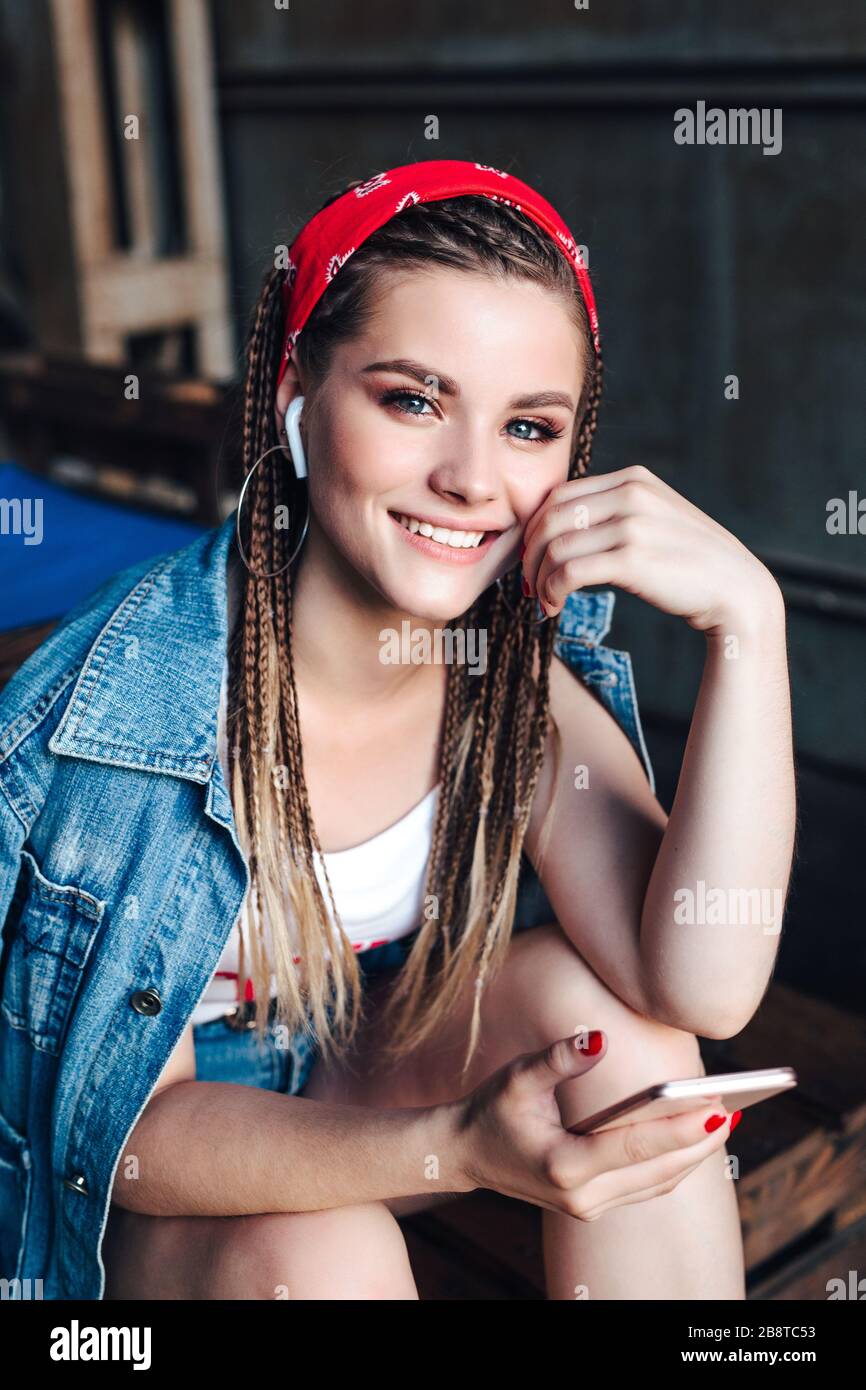 joven mujer hipster con bandana y trenzas usando smartphone en la cafetería  de la calle de la ciudad Fotografía de stock - Alamy