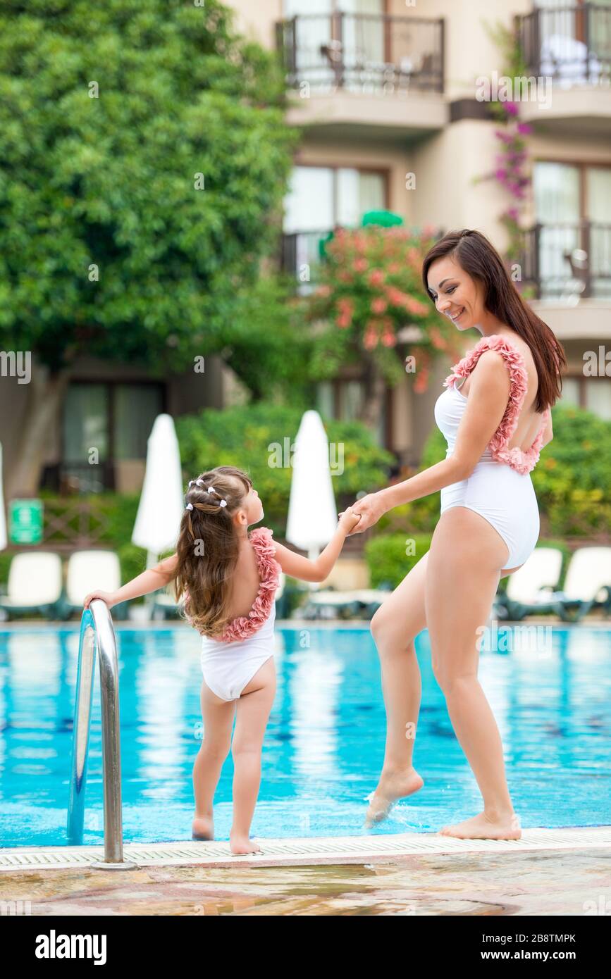 Mamá joven con su hija en los mismos bañadores blancos están en el borde de  la piscina. Ropa para el verano y el mar familiar Fotografía de stock -  Alamy