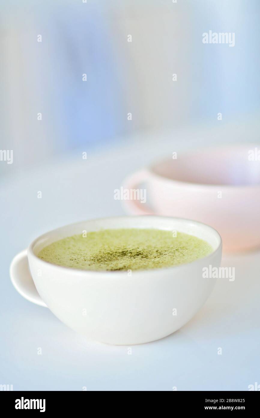 Taza blanca con matte matcha sobre una mesa blanca, una taza rosa claro sobre el fondo, té verde Matcha latte en una taza. Vista superior. Espacio de copia. Alfombra de té verde Foto de stock
