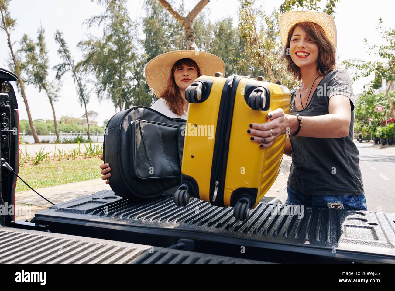 Alegres amigas poniendo maletas en la parte trasera de su camión y  preparándose para un largo viaje en carretera Fotografía de stock - Alamy