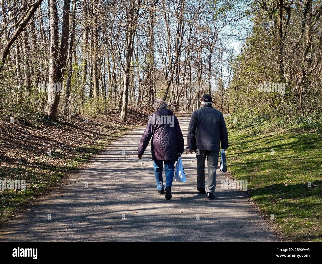 Munich, Baviera, Alemania. 23 de marzo de 2020. Una pareja va a dar un paseo por Munich, Alemania, mostrando la nueva normalidad de la llamada "Kontaktverbot", que restringe los contactos a un máximo de dos personas eho que viven en el mismo hogar. Los grupos más grandes estarán sujetos a multas en virtud de la Infektionsschutzgesetz para frenar la propagación de Covid-19 (SARS COV 2) a través de lugares de reunión públicos. Crédito: Sachelle Babbar/ZUMA Wire/Alamy Live News Foto de stock