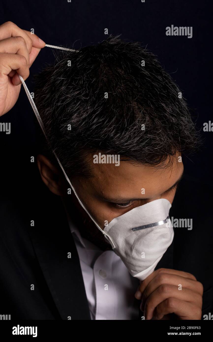 Joven guapo con máscara médica para prevenir la propagación de virus contagiosos o gases químicos Foto de stock