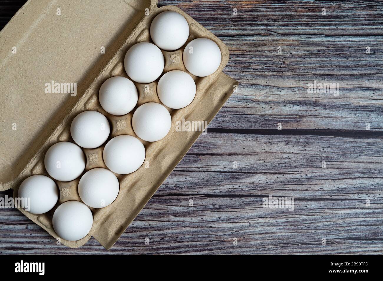 Huevos de pollo en la caja de huevos sobre fondo de madera oxidada Foto de stock