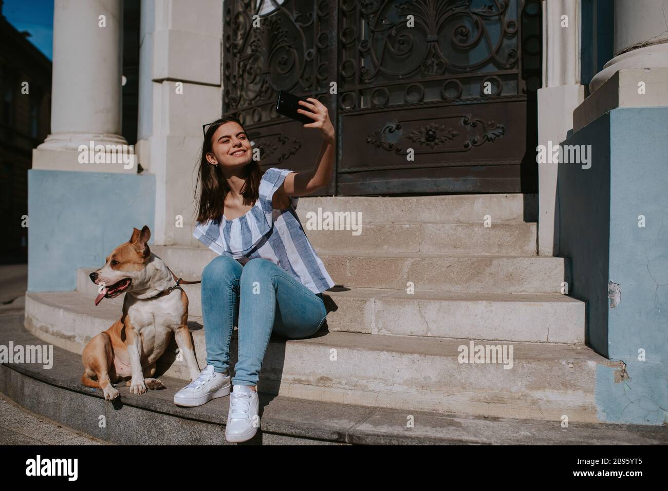 Joven hermosa niña hace selfies de ella y su perro en las escaleras del  edificio Fotografía de stock - Alamy