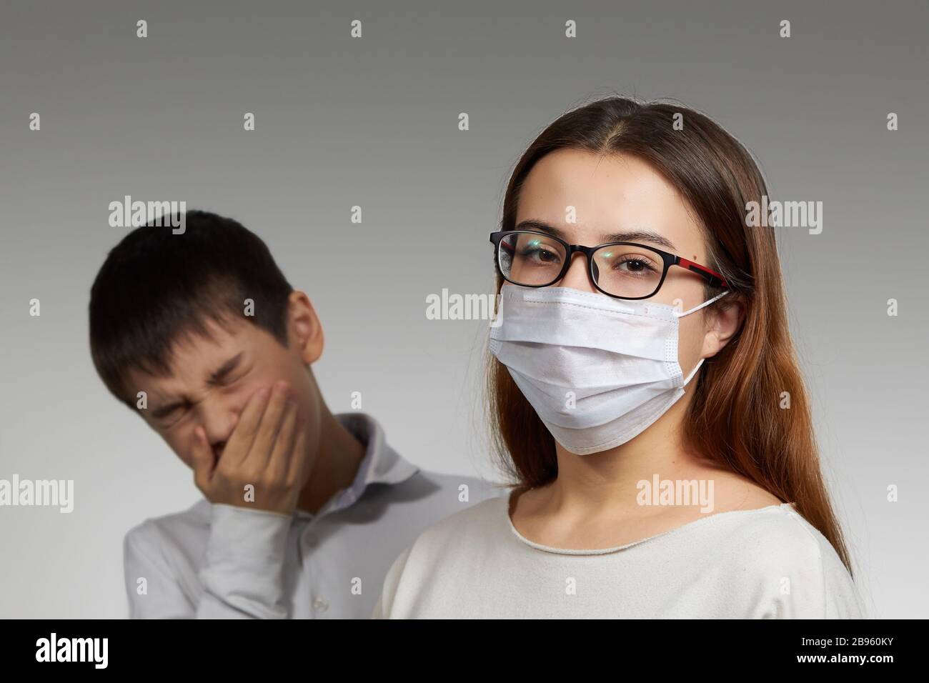 estornudos enmascarados de niña y niño, el concepto de protección contra la propagación de la máscara médica del virus. Foto de stock