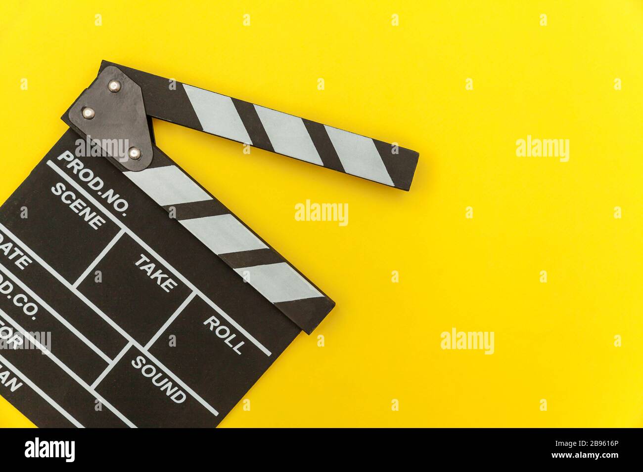 Profesión de cineasta. Película vacía de director clásico haciendo  clapperboard o pizarra de película aislada sobre fondo amarillo. Producción  de vídeo cine concepto de la industria cinematográfica. Plano de la parte  superior