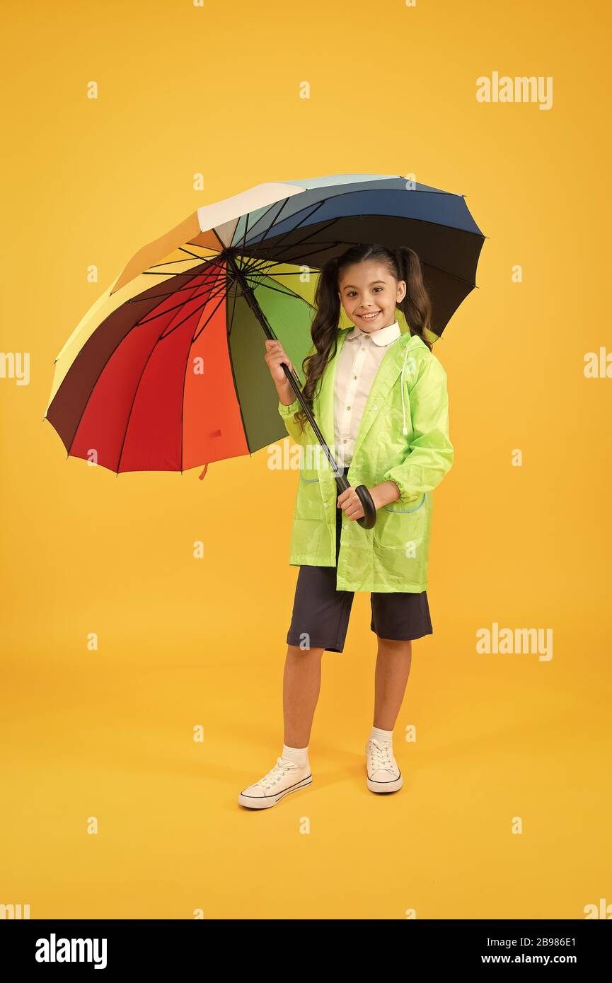 Alumna despreocupada coloridos paraguas chubasquero impermeable de desgaste. Lluvia de Ir a la escuela los días de lluvia más diversión con brillantes accesorios. La lluvia no es tan malo si tiene
