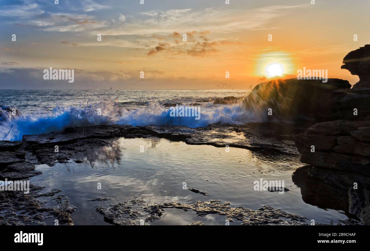 Sol naciente sobre el horizonte y rocas de arenisca de Turimetta cabeza de las playas del norte de Sydney. Foto de stock