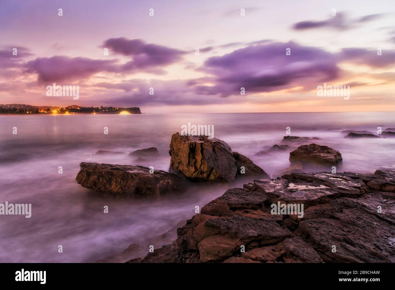 Las rocas de arenisca mojada de Turimetta se dirigen a las playas del norte de Sydney al amanecer. Foto de stock