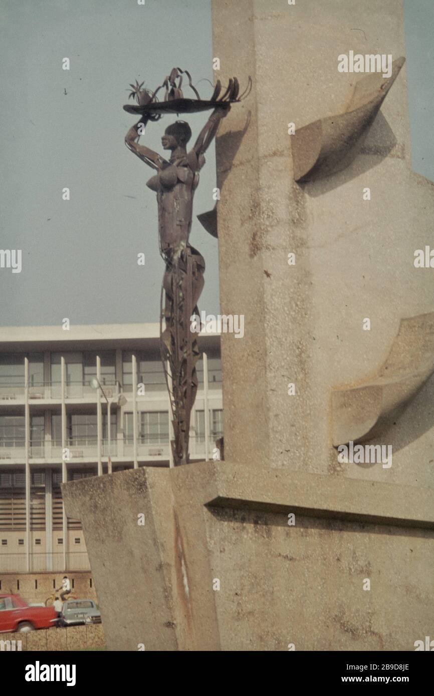 Símbolo de fertilidad ('Chica con la fruta') como monumento con la Oficina General de correos en el fondo en la Place de la REPUBLICIN Abidjan. [traducción automática] Foto de stock