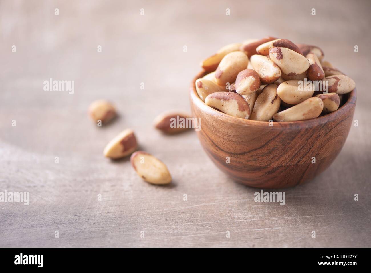 Nueces de Brasil en cuenco de madera sobre fondo texturizado de madera. Espacio de copia. Superfood, vegan, comida vegetariana concepto. Macro de la textura de la nuez de brasil, selectiva Foto de stock