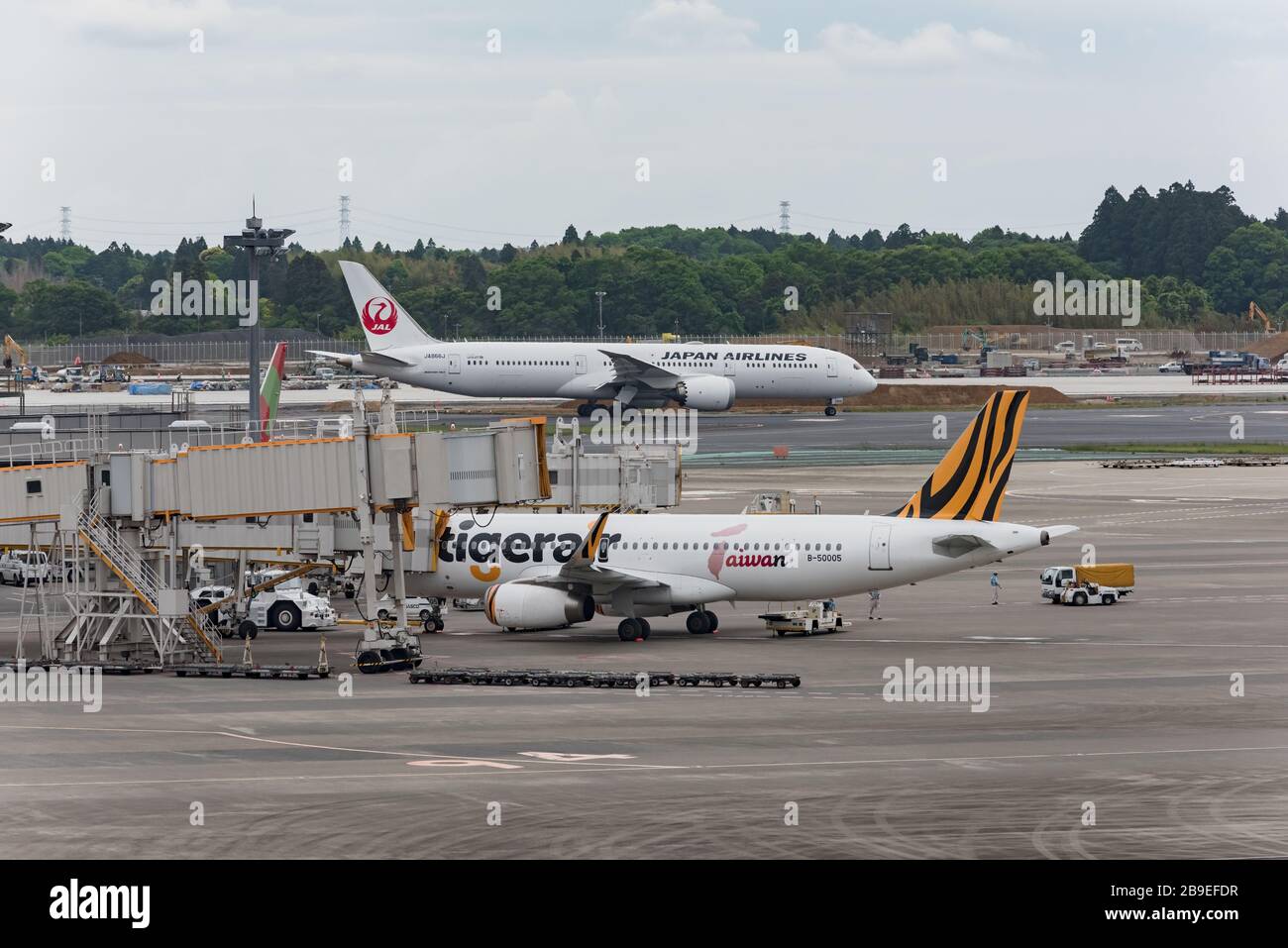 Narita, Japón - 15 de mayo de 2019: Sosteniendo un delantal del Aeropuerto Internacional de Narita, aviones de Japan Airlines y Tigerar Airlines están esperando para despegar. Foto de stock