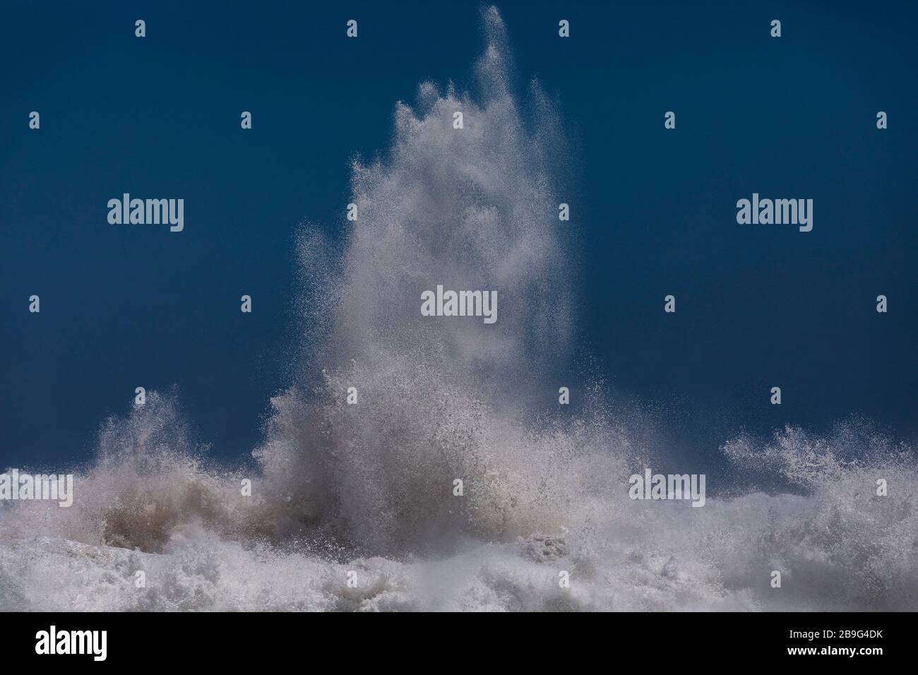 Potente ola oceánica que se rompe contra el cielo azul Foto de stock