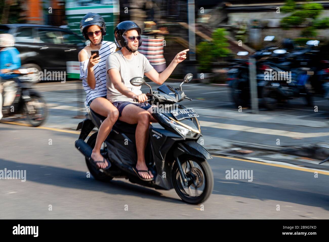 Los turistas que utilizan una aplicación para navegar por su camino aroung Ubud, personas que viajan en motocicleta, Ubud, Bali, Indonesia. Foto de stock