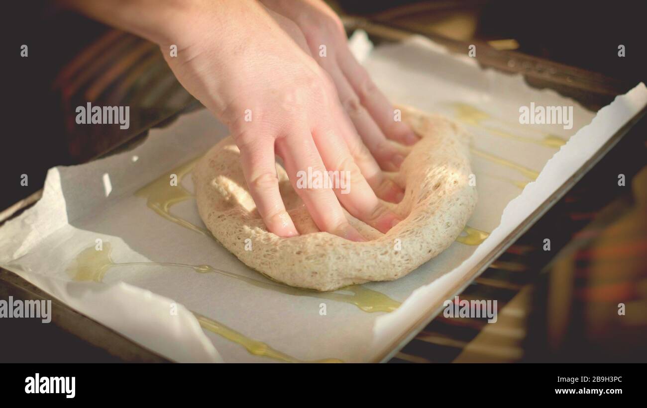 pizza horizontal masa fondo cocina italiana manos sobre la masa en la hoja de pan de aceite de oliva casero rústico Foto de stock