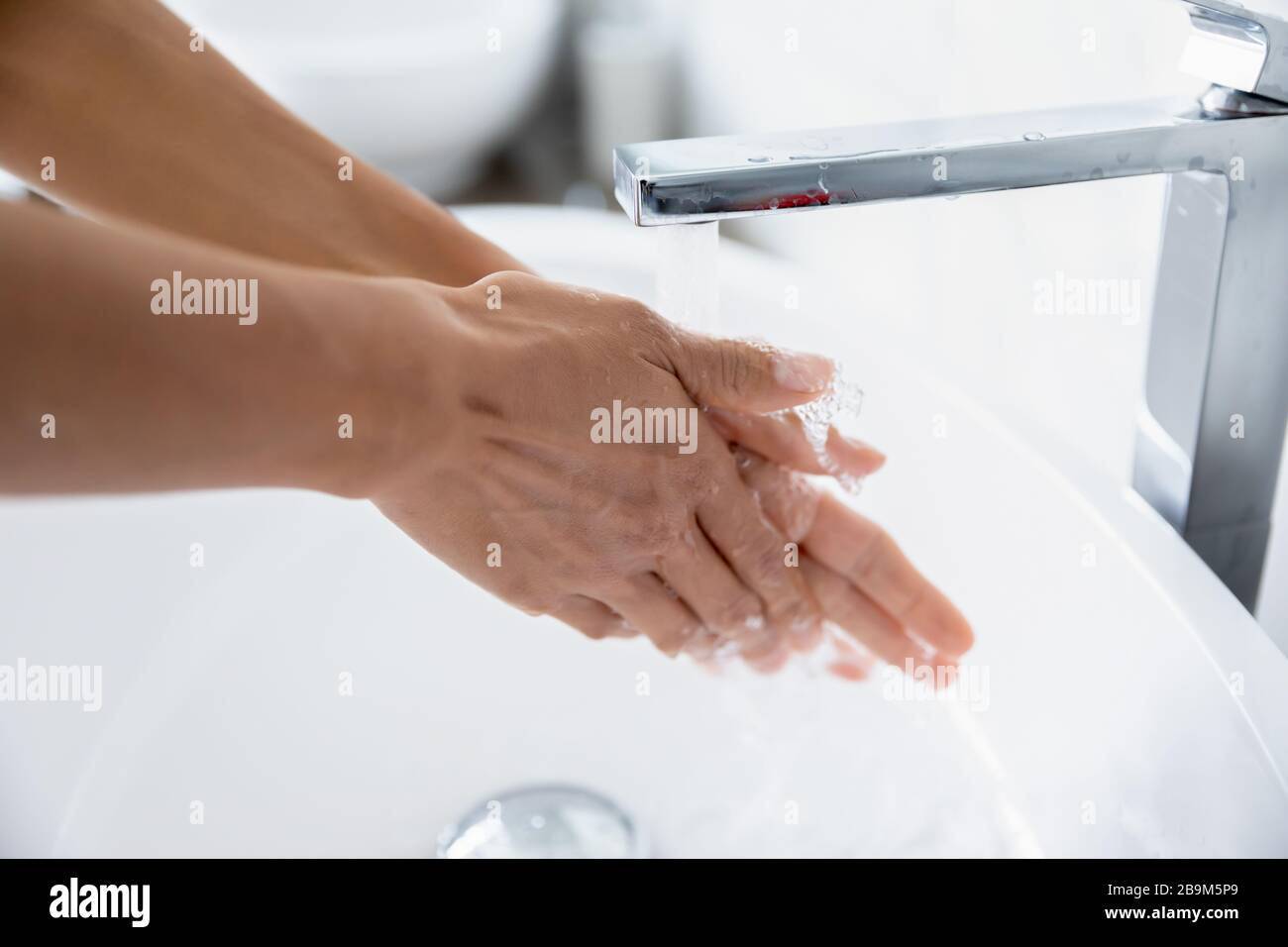 Vista de primer plano mujer limpia las manos bajo el agua corriente del grifo Foto de stock