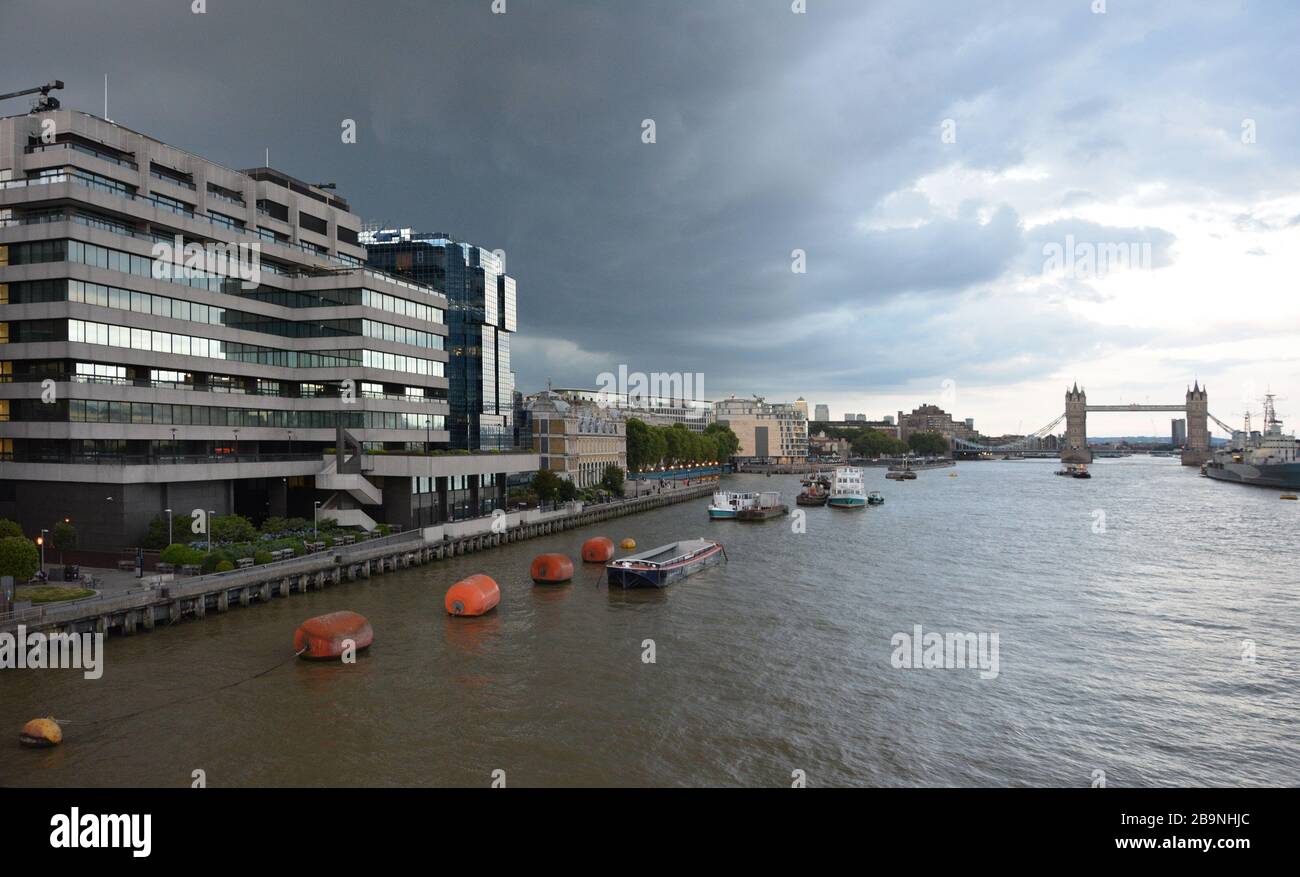 Edificios en el lado norte del río Támesis, desde el puente de Londres mirando al este, con el puente de la torre a una distancia. El día está nublado Foto de stock