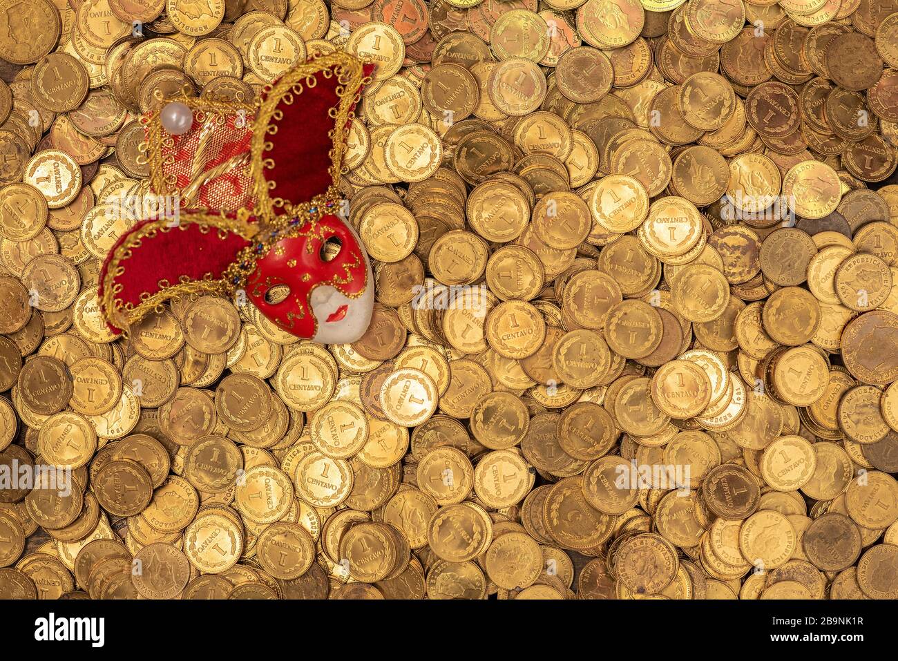 Pila de pequeñas monedas de oro con máscara veneciana Foto de stock