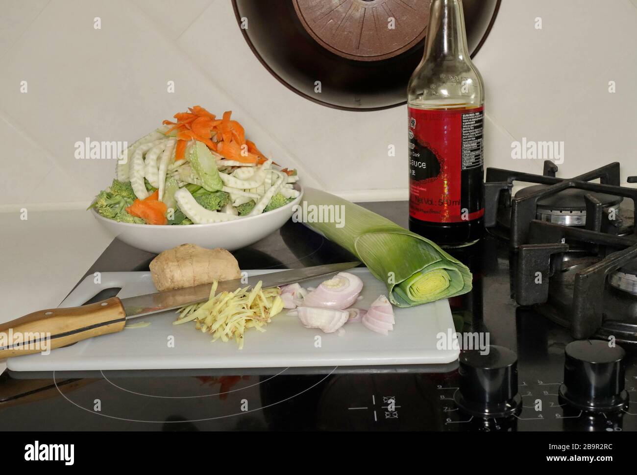 Cortar verduras crudas y trituradas en una estufa en una despensa preparada para un plato de wok simple. Foto de stock