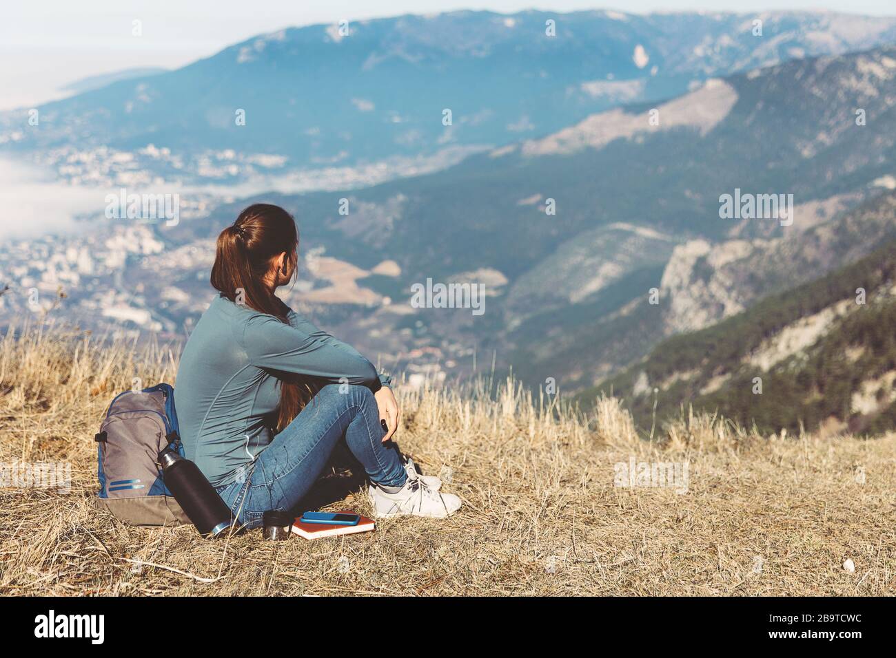 Una joven hermosa niña viaja sola en las montañas en primavera o otoño, se  encuentra en el borde de la montaña y mira a la distancia y disfruta de la  naturaleza, rocas