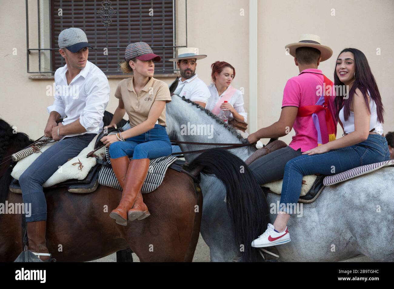 Las parejas jóvenes viajan a caballo por las calles durante un festival de verano en Monachil, Granada, Andalucía, España Foto de stock