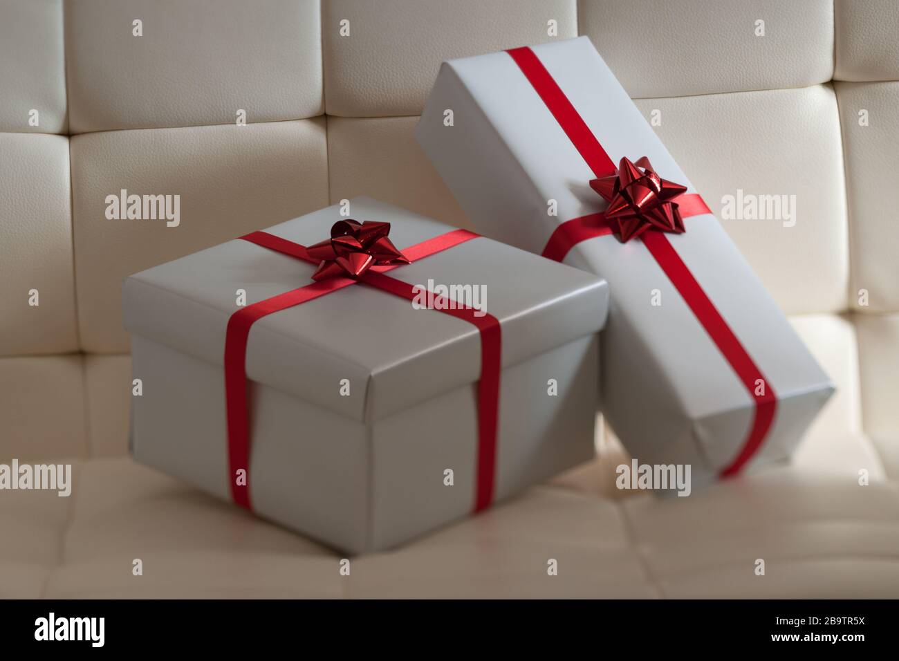 Dos regalos envueltos en regalo en silla acolchada blanca Foto de stock