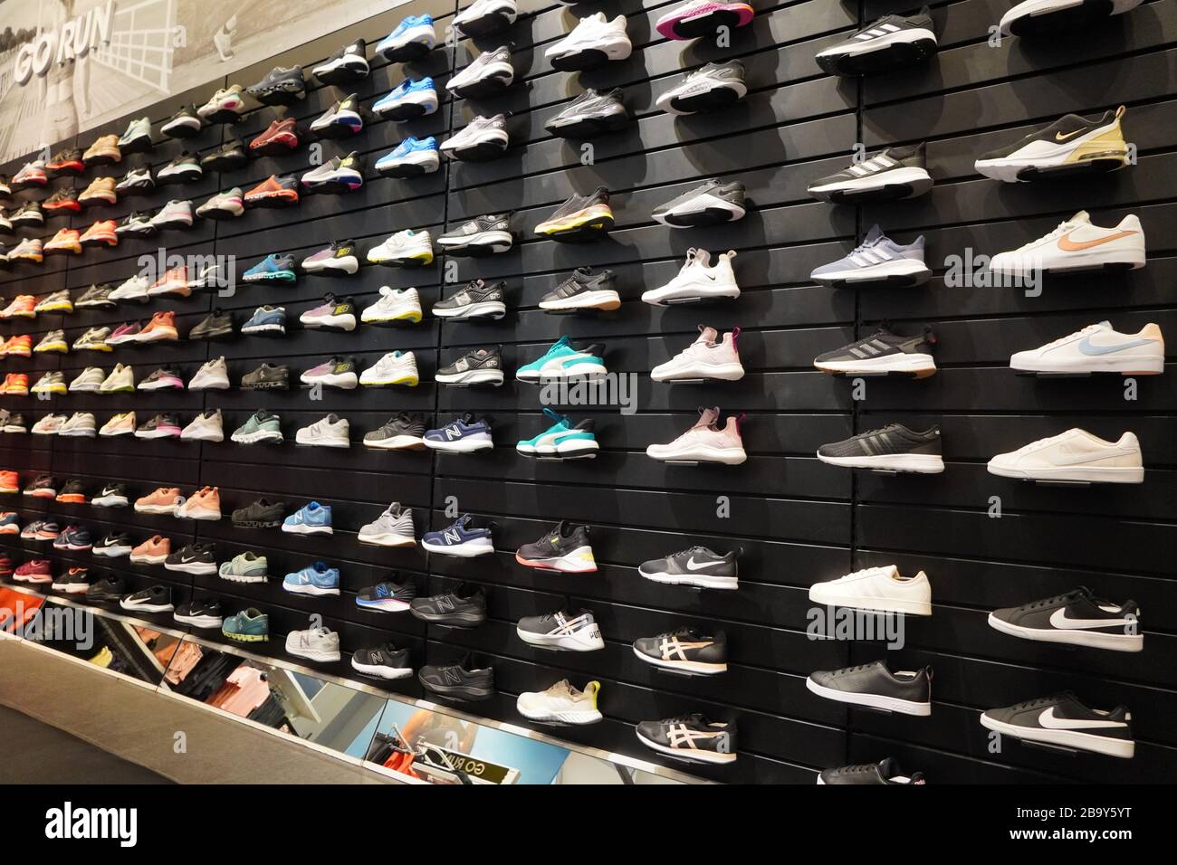 Ver la exhibición de muchos zapatos deportivos en una pared. Una de una pared de zapatos dentro de la tienda. Nuevas y modernas zapatillas de running con estilo para hombre y