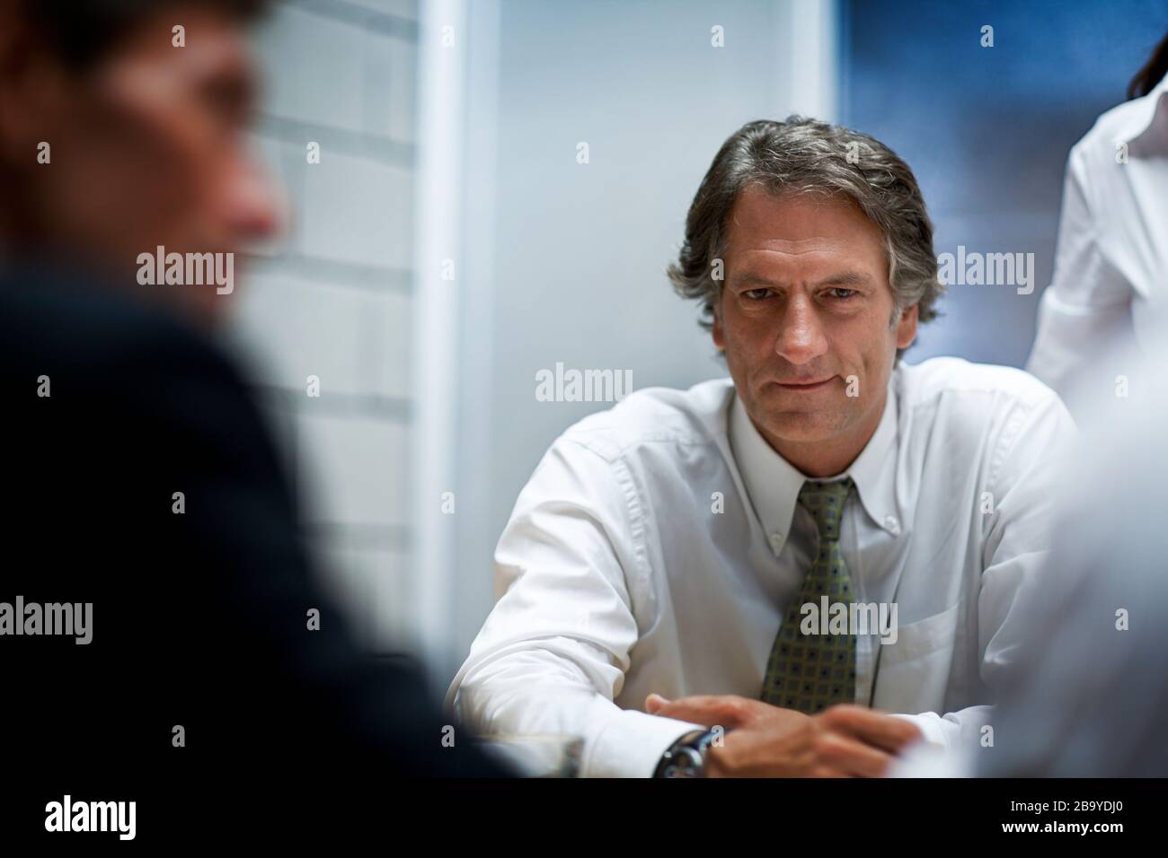 Businessman poses para una portait mientras se sienta en una mesa durante una reunión de negocios. Foto de stock