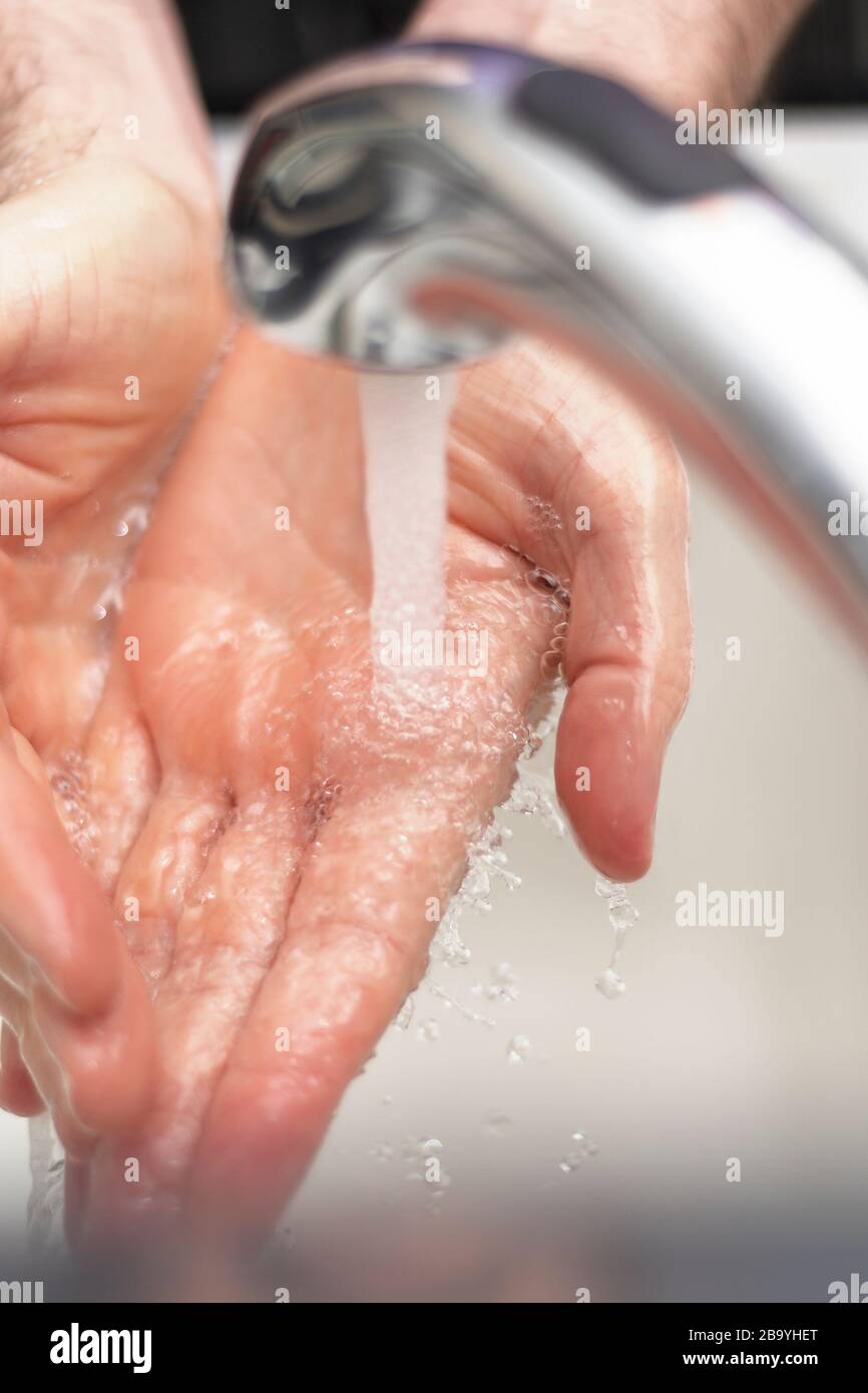 Manos debajo del grifo lavándose con jabón y agua caliente, vertical. Foto de stock