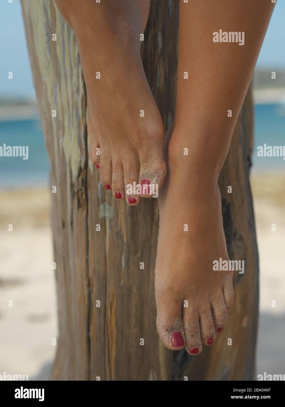 Pies descalzos con clavos pintados en la playa Foto de stock