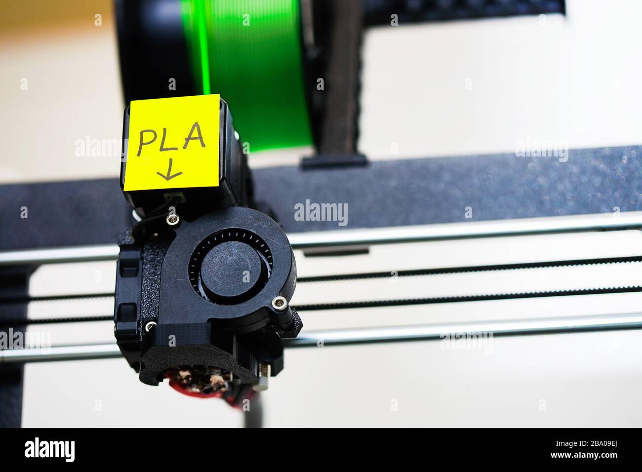 Una impresora 3d que utiliza filamento de tipo PLA y muestra el cabezal de impresión y el eje x. Foto de stock