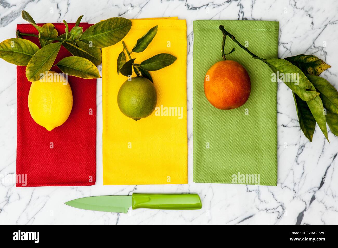 limón, lima y naranja sanguã neo con cuchillo de paring en mostrador de mármol Foto de stock