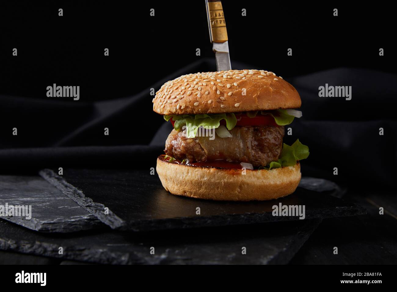 hamburguesa perforada por cuchillo en madera oscura tabla de corte aislada  en negro Fotografía de stock - Alamy