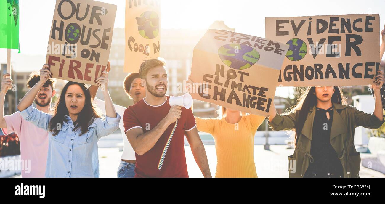 Grupo de manifestantes en la carretera, jóvenes de diferentes culturas y razas luchan por el cambio climático - concepto de calentamiento global y medio ambiente - Focus Foto de stock