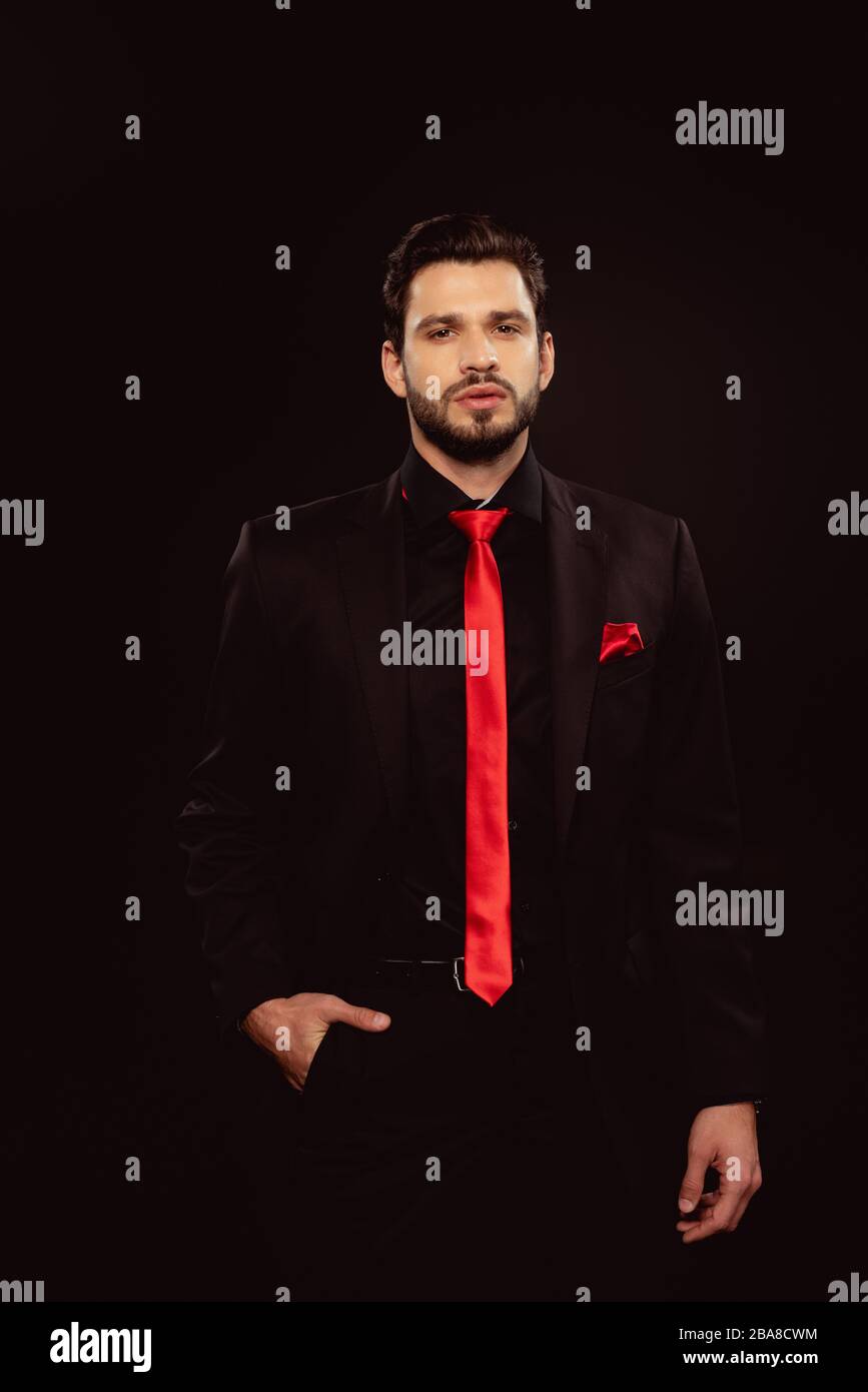 Hombre guapo en traje y corbata roja mirando a la cámara aislada en negro  Fotografía de stock - Alamy