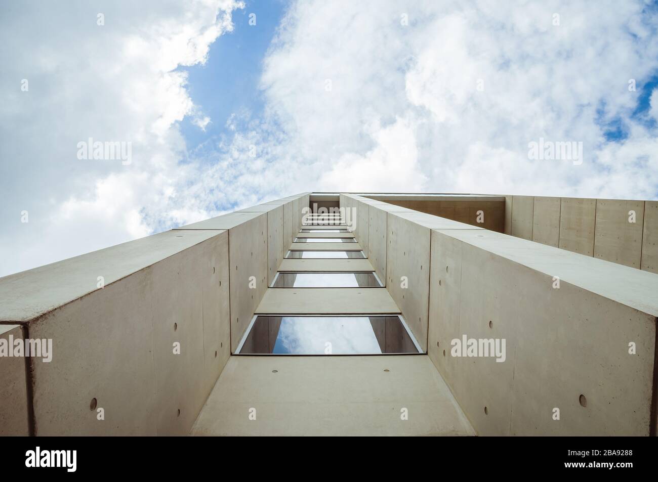 Hermosos detalles arquitectónicos de un edificio moderno de hormigón y fibra de vidrio, con vistas a un cielo azul nublado Foto de stock