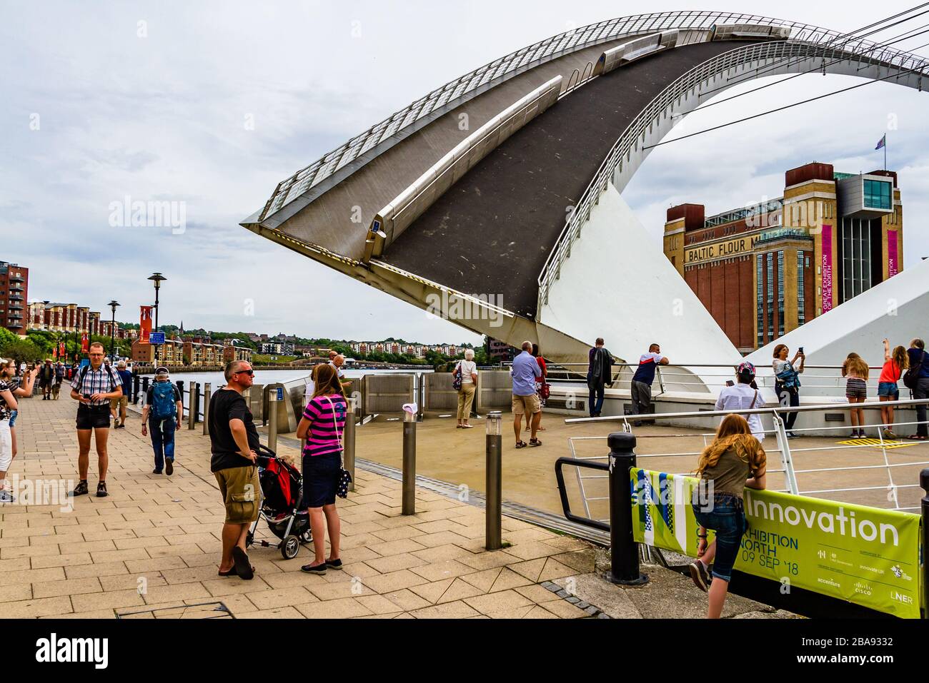 Gateshead Millennium Bridge, un puente basculante, levantado para dejar pasar los barcos mientras la gente espera y mira. Newcastle upon Tyne, Reino Unido. Agosto de 2018. Foto de stock