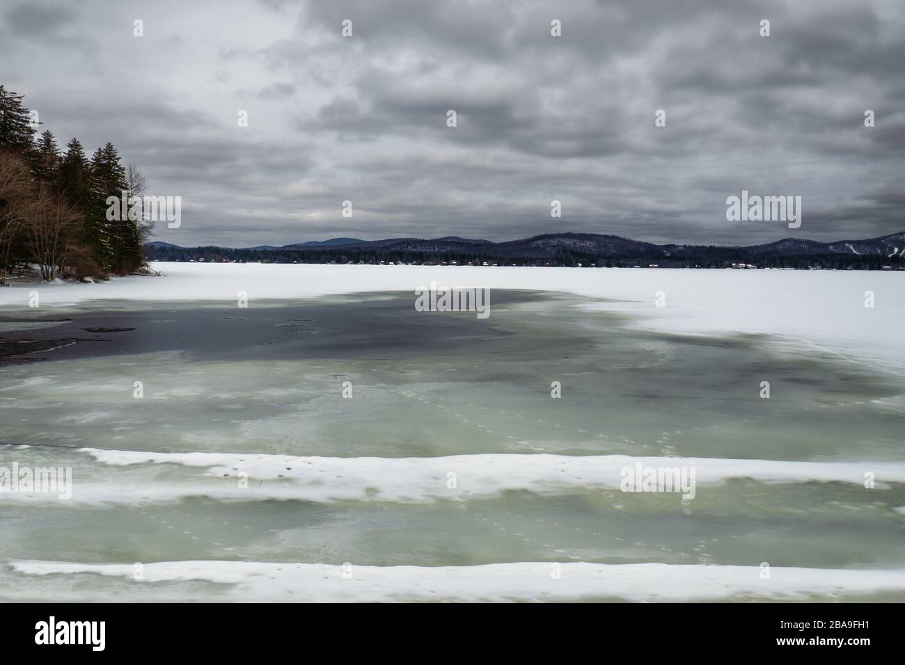 Tranquilo paisaje de montaña y lago congelado en las Montañas Adirondack del upstate Nueva York Foto de stock